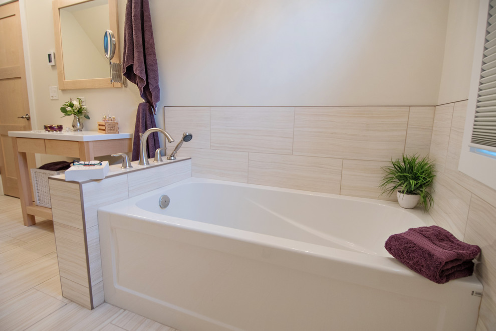 Photo of a small transitional master bathroom in Vancouver with white cabinets, solid surface benchtops, porcelain tile, flat-panel cabinets, a corner tub, a two-piece toilet, beige walls, vinyl floors and an undermount sink.