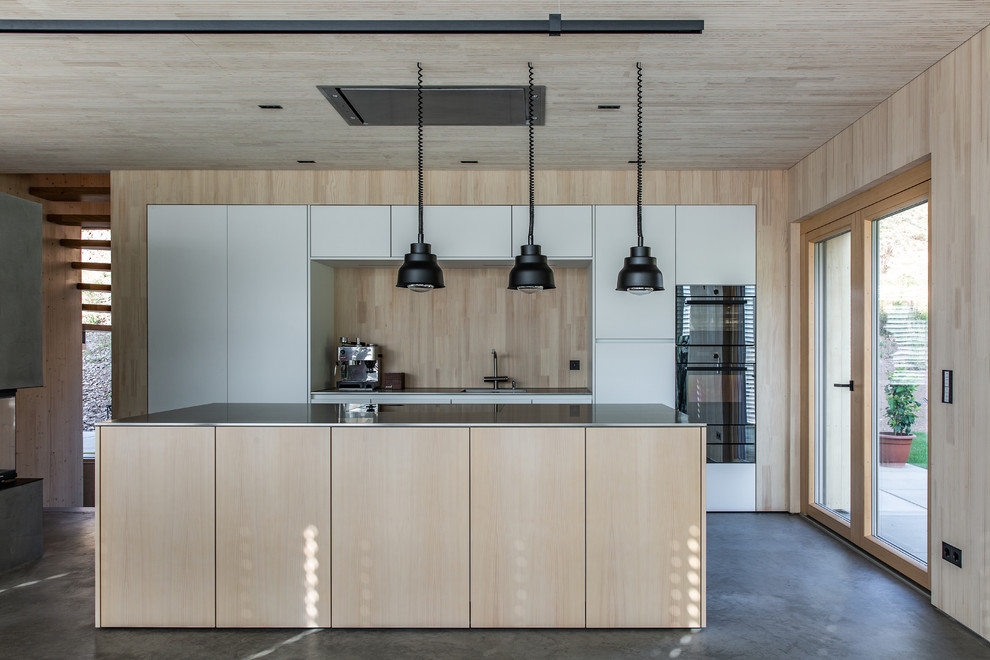 Photo of a modern galley kitchen in Other with flat-panel cabinets, white cabinets, beige splashback, timber splashback, stainless steel appliances, concrete floors, with island, grey floor and grey benchtop.