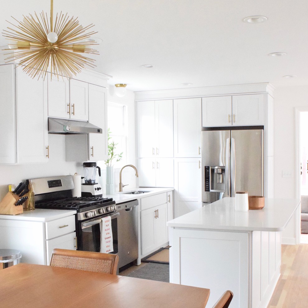 This is an example of a mid-sized contemporary eat-in kitchen in Nashville with white cabinets, marble benchtops, white splashback, subway tile splashback, stainless steel appliances, light hardwood floors, with island and brown floor.