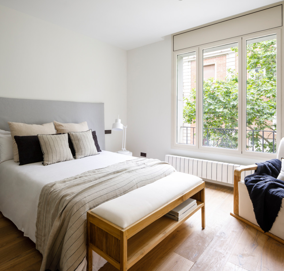 На фото: большая хозяйская спальня в стиле модернизм с белыми стенами, полом из ламината и коричневым полом с