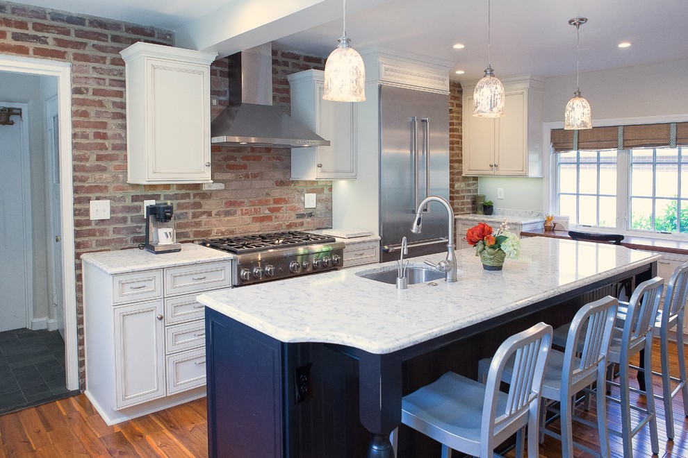 Example of a large transitional medium tone wood floor eat-in kitchen design with an undermount sink, recessed-panel cabinets, black cabinets, quartz countertops, brick backsplash, stainless steel appliances and an island