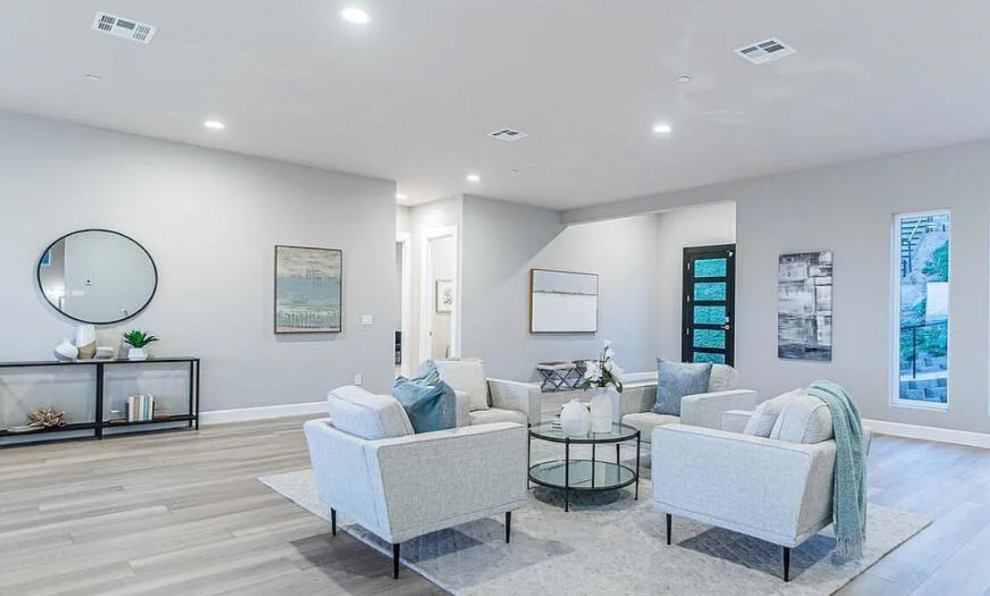 Geräumiges, Offenes Modernes Wohnzimmer mit weißer Wandfarbe, hellem Holzboden, Kamin, grauem Boden und Kaminumrandung aus Metall in San Diego