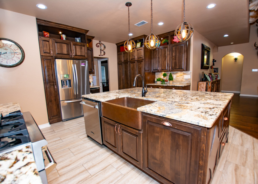 Kitchen - transitional porcelain tile and beige floor kitchen idea in Austin with a farmhouse sink, raised-panel cabinets, dark wood cabinets, granite countertops, stone tile backsplash, stainless steel appliances and an island