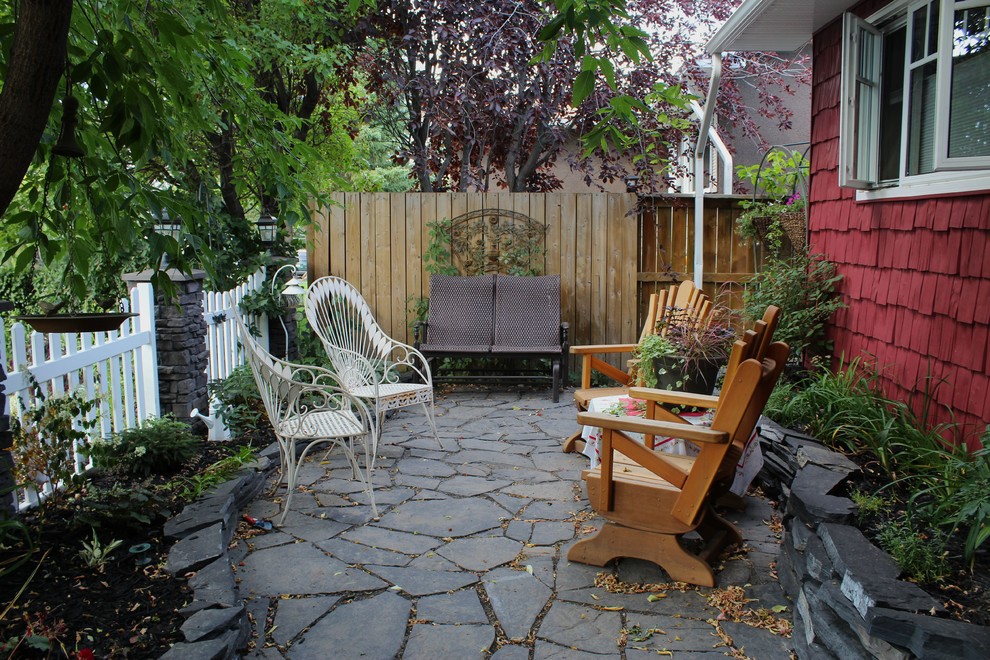 Design ideas for a traditional courtyard patio in Calgary with natural stone pavers.
