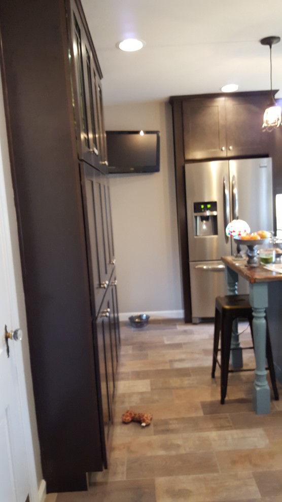 Eat-in kitchen - mid-sized rustic u-shaped porcelain tile eat-in kitchen idea in Indianapolis with a farmhouse sink, shaker cabinets, dark wood cabinets, wood countertops, white backsplash, ceramic backsplash, stainless steel appliances and an island