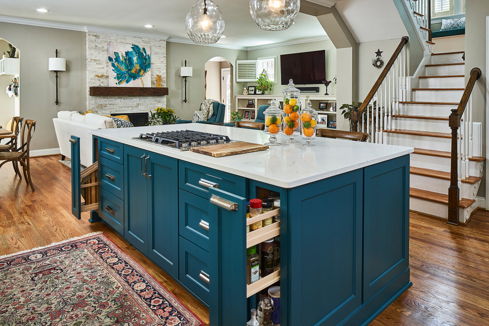 Mid-sized transitional u-shaped open plan kitchen in Charlotte with an undermount sink, recessed-panel cabinets, turquoise cabinets, quartz benchtops, blue splashback, glass tile splashback, stainless steel appliances, medium hardwood floors, with island, brown floor, white benchtop and exposed beam.