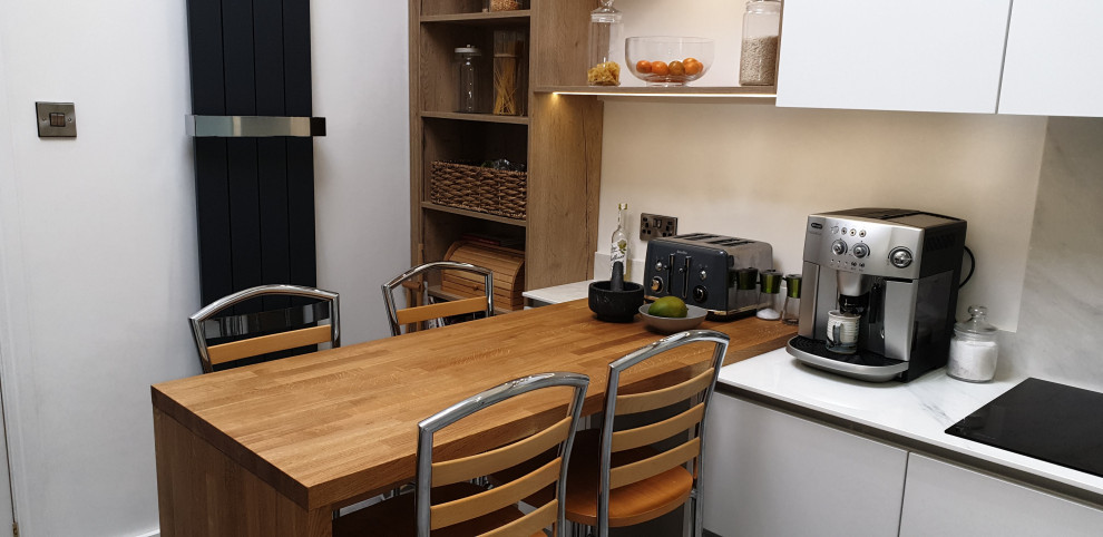 Photo of a large modern u-shaped eat-in kitchen in Other with an undermount sink, flat-panel cabinets, white cabinets, onyx benchtops, white splashback, black appliances, linoleum floors, with island, grey floor and white benchtop.