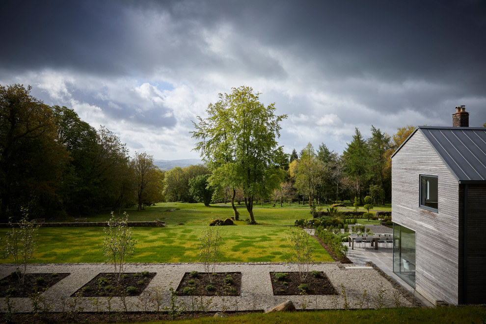 На фото: большой регулярный сад на переднем дворе в современном стиле с дорожками и покрытием из гравия с