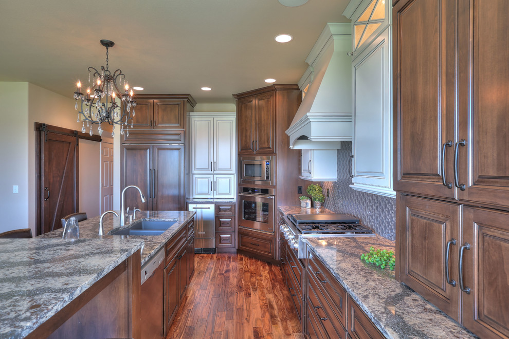 Inspiration for a large transitional l-shaped medium tone wood floor eat-in kitchen remodel in Seattle with an undermount sink, medium tone wood cabinets, granite countertops, brown backsplash, stainless steel appliances and an island