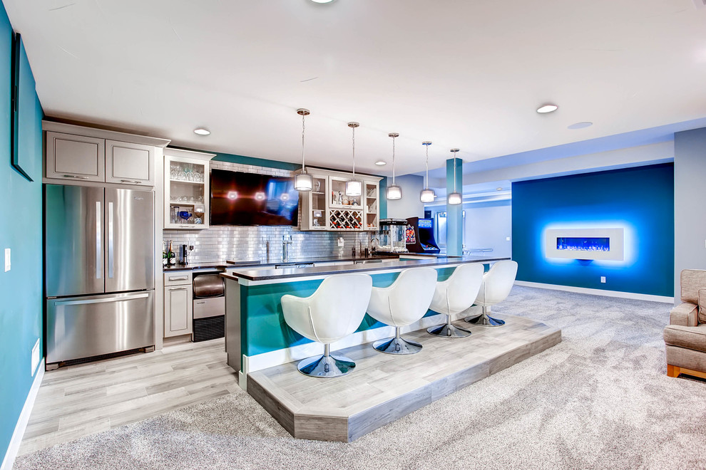 Photo of a large contemporary galley seated home bar in Denver with an undermount sink, glass-front cabinets, white cabinets, solid surface benchtops, metal splashback, carpet, grey floor and black benchtop.