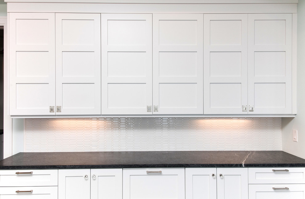 Example of a large transitional u-shaped dark wood floor eat-in kitchen design in New York with an undermount sink, shaker cabinets, white cabinets, soapstone countertops, white backsplash, subway tile backsplash, paneled appliances and an island