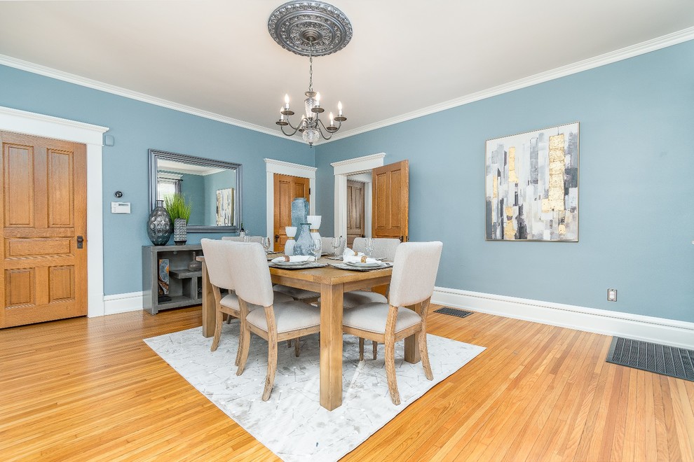This is an example of a mid-sized transitional separate dining room in Columbus with blue walls, light hardwood floors and brown floor.