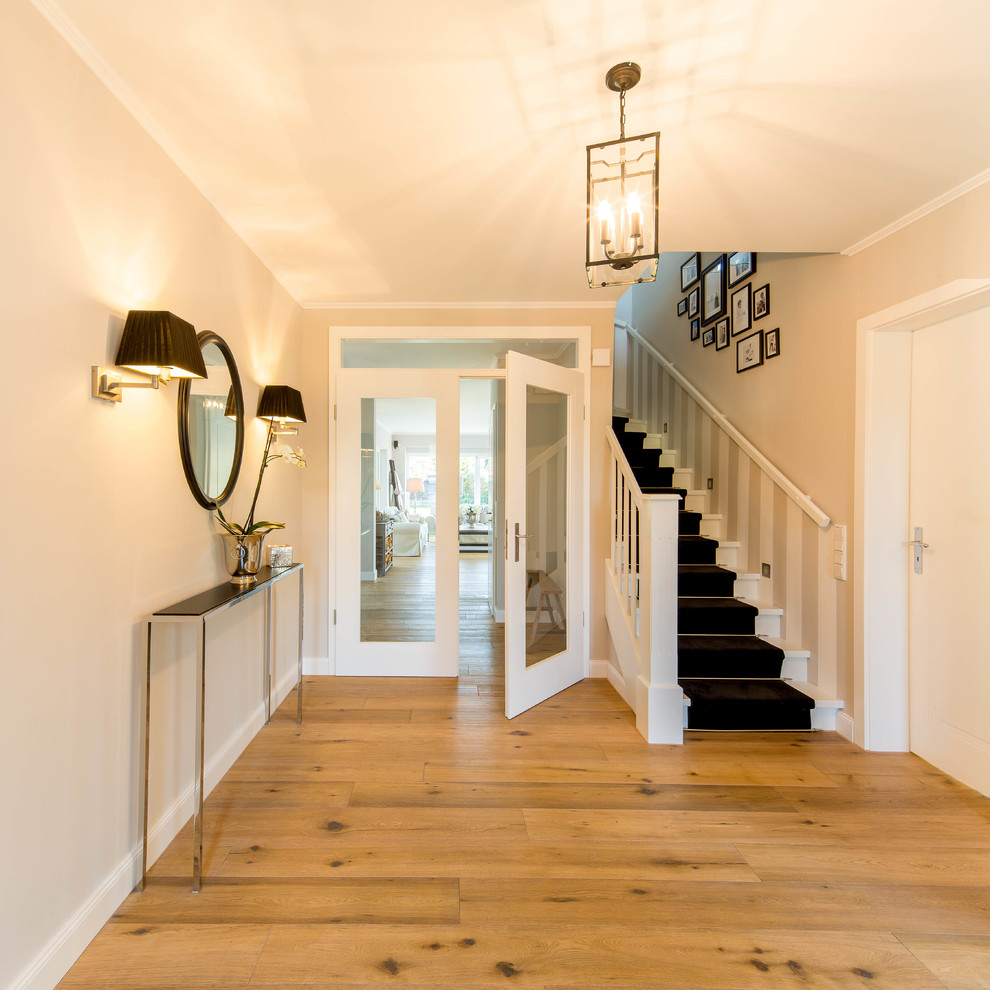 Inspiration for a mid-sized traditional foyer in Dusseldorf with beige walls, medium hardwood floors, a single front door and a white front door.