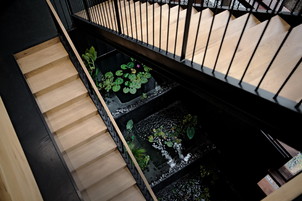 Ejemplo de escalera actual extra grande con escalones de metal, contrahuellas de madera, barandilla de metal y madera
