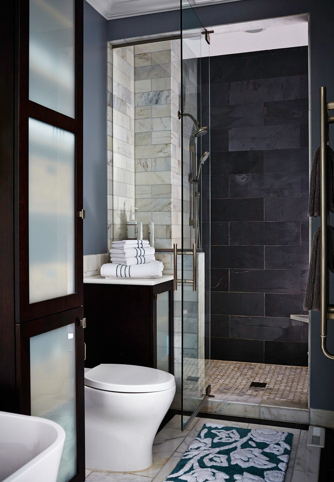Inspiration for a mid-sized transitional master bathroom in Other with a freestanding tub, an alcove shower, gray tile, an undermount sink, glass-front cabinets, dark wood cabinets, engineered quartz benchtops, a one-piece toilet, grey walls and slate.