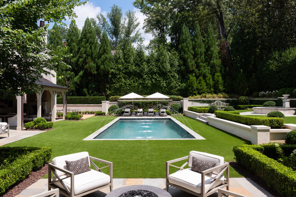 Photo of an expansive traditional backyard rectangular lap pool in Atlanta with a water feature and natural stone pavers.