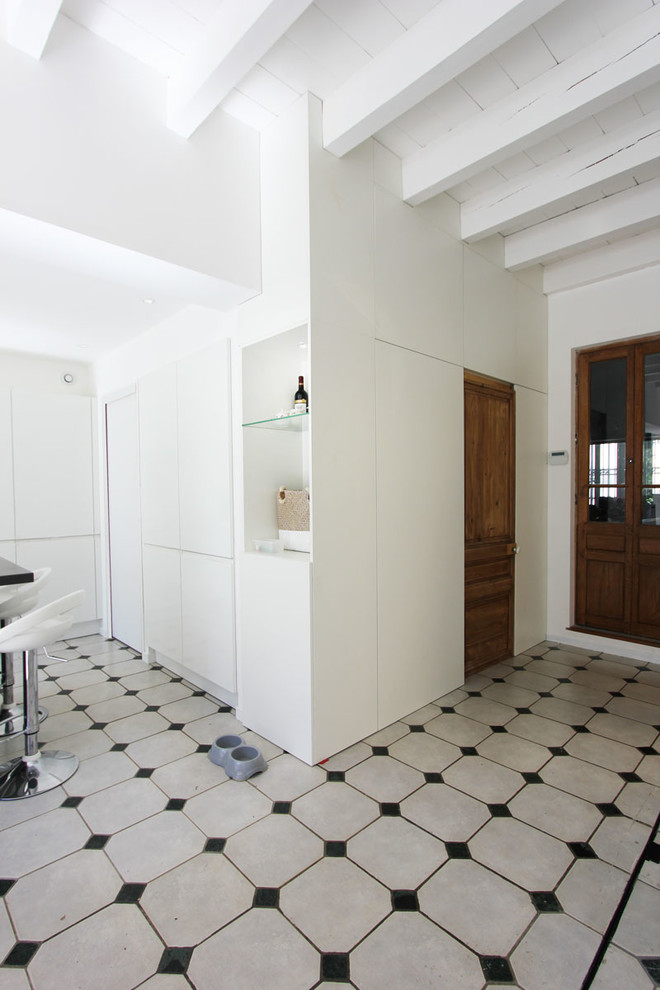 Large eclectic galley eat-in kitchen in Lyon with an undermount sink, white cabinets, black splashback, stainless steel appliances, marble floors, with island, flat-panel cabinets, slate splashback, multi-coloured floor and black benchtop.