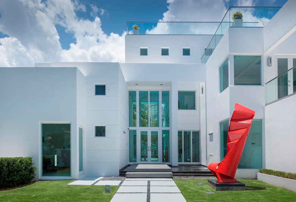 This is an example of a contemporary three-storey white exterior in Miami with a flat roof.