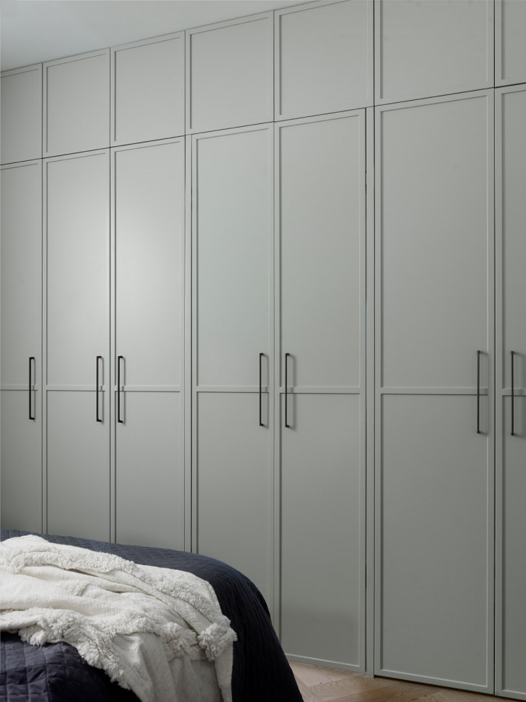 Réalisation d'une grande armoire encastrée design neutre avec un placard à porte shaker et des portes de placard grises.