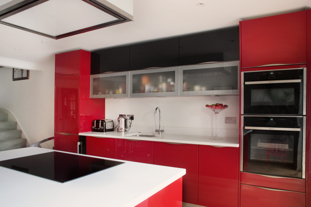 Mid-sized contemporary single-wall eat-in kitchen in Buckinghamshire with red cabinets, quartzite benchtops, stainless steel appliances, light hardwood floors, with island, an integrated sink and flat-panel cabinets.