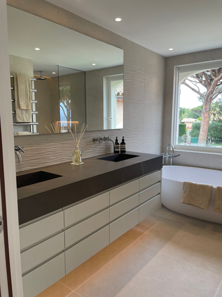 Photo of a large contemporary master bathroom in Other with beaded inset cabinets, white cabinets, a drop-in tub, beige tile, ceramic tile, beige walls, ceramic floors, a console sink, tile benchtops, beige floor, brown benchtops, a double vanity and a floating vanity.