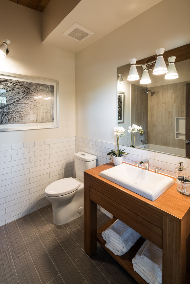 This is an example of a country master bathroom in Los Angeles with flat-panel cabinets, dark wood cabinets, a freestanding tub, a corner shower, a bidet, beige tile, ceramic floors and a pedestal sink.