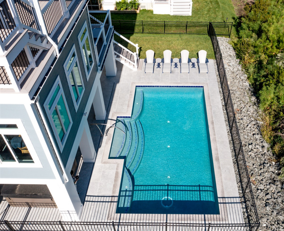 На фото: бассейн среднего размера, произвольной формы на заднем дворе в морском стиле с покрытием из плитки