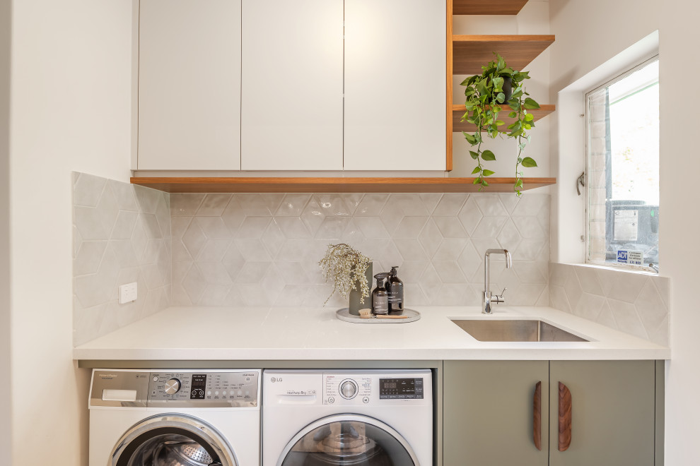 Small contemporary single-wall dedicated laundry room in Adelaide with an undermount sink, flat-panel cabinets, green cabinets, quartz benchtops, grey splashback, porcelain splashback, white walls, ceramic floors, a side-by-side washer and dryer, grey floor and white benchtop.