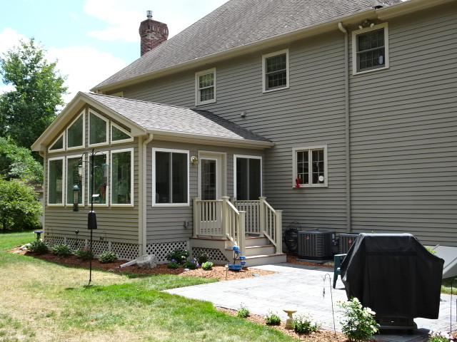 Photo of an expansive traditional two-storey grey exterior in Boston with concrete fiberboard siding and a clipped gable roof.