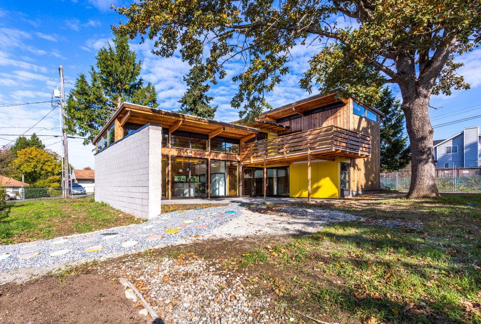 Ispirazione per la facciata di una casa gialla moderna a due piani di medie dimensioni con tetto bianco, pannelli e listelle di legno e rivestimenti misti
