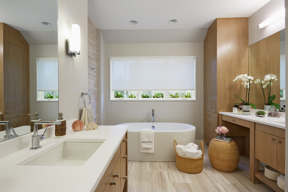 Photo of a contemporary master bathroom in Minneapolis with flat-panel cabinets, light wood cabinets, quartzite benchtops, a freestanding tub, beige tile, stone tile, grey walls, ceramic floors and an undermount sink.