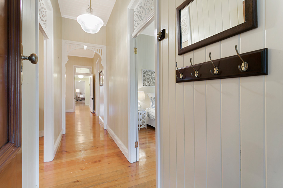 Cette image montre une grande porte d'entrée victorienne avec un mur beige, parquet clair, une porte simple, une porte en bois brun, un sol marron, un plafond en lambris de bois et du lambris de bois.