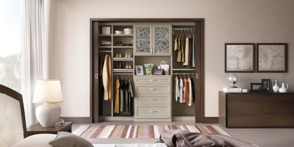 This is an example of a mid-sized contemporary women's built-in wardrobe in Nashville with light wood cabinets and carpet.