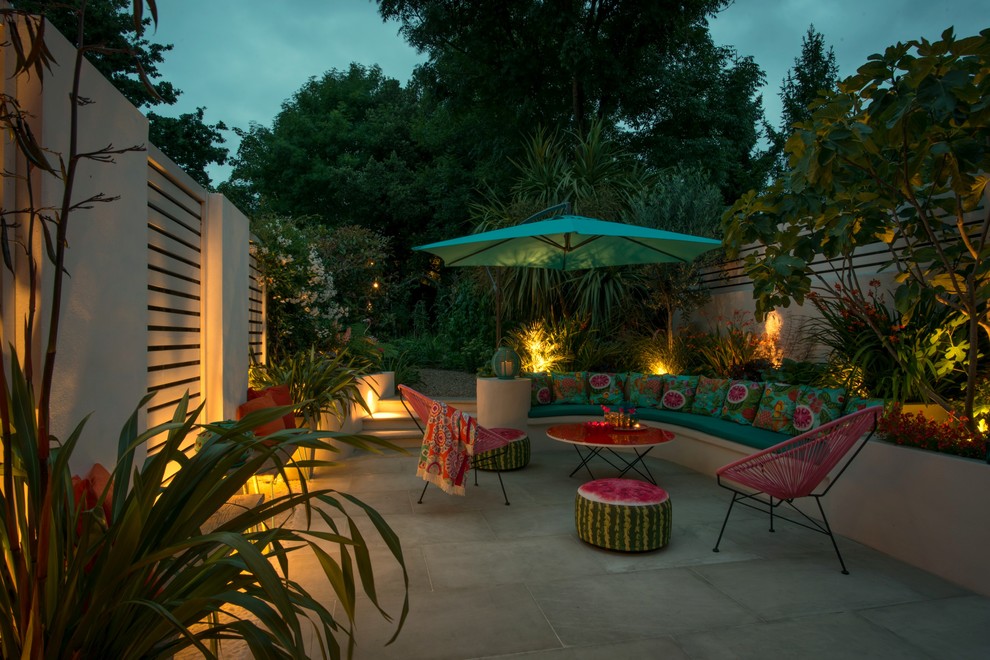 Design ideas for a mid-sized eclectic backyard garden in London with natural stone pavers.