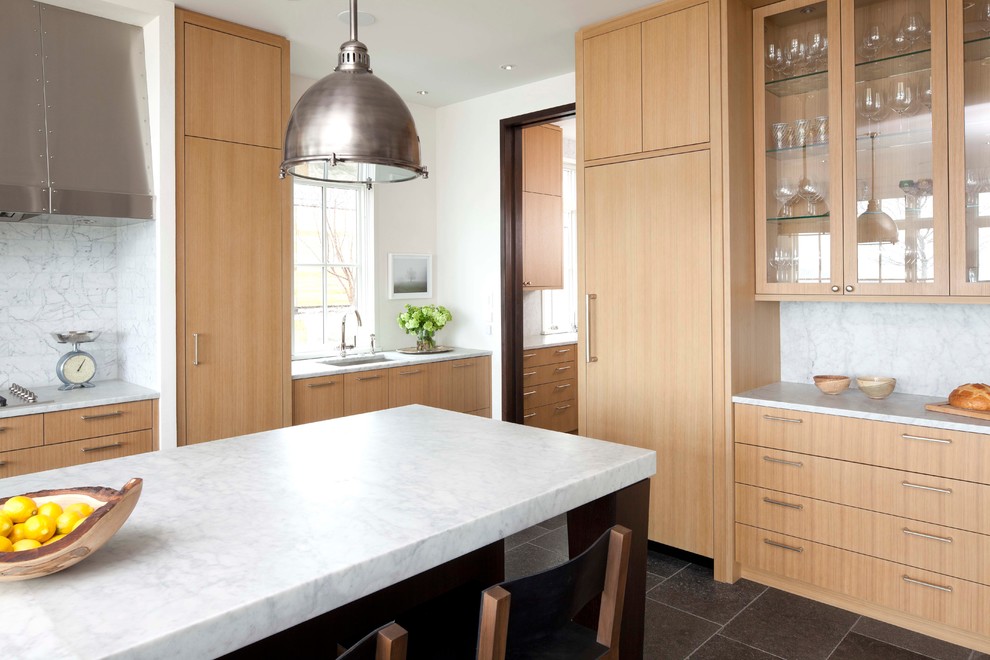 This is an example of a transitional l-shaped open plan kitchen in Minneapolis with an undermount sink, flat-panel cabinets, light wood cabinets, marble benchtops, multi-coloured splashback, limestone floors and with island.