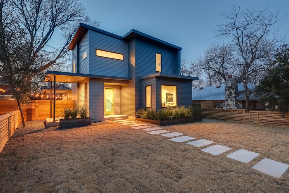 This is an example of a mid-sized midcentury two-storey grey house exterior in Austin with a flat roof, a green roof and wood siding.