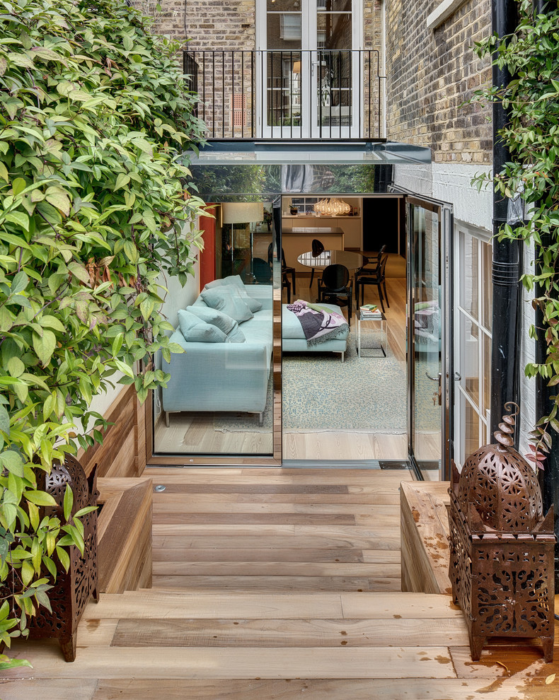 This is an example of a small contemporary backyard deck in London with a vertical garden and no cover.
