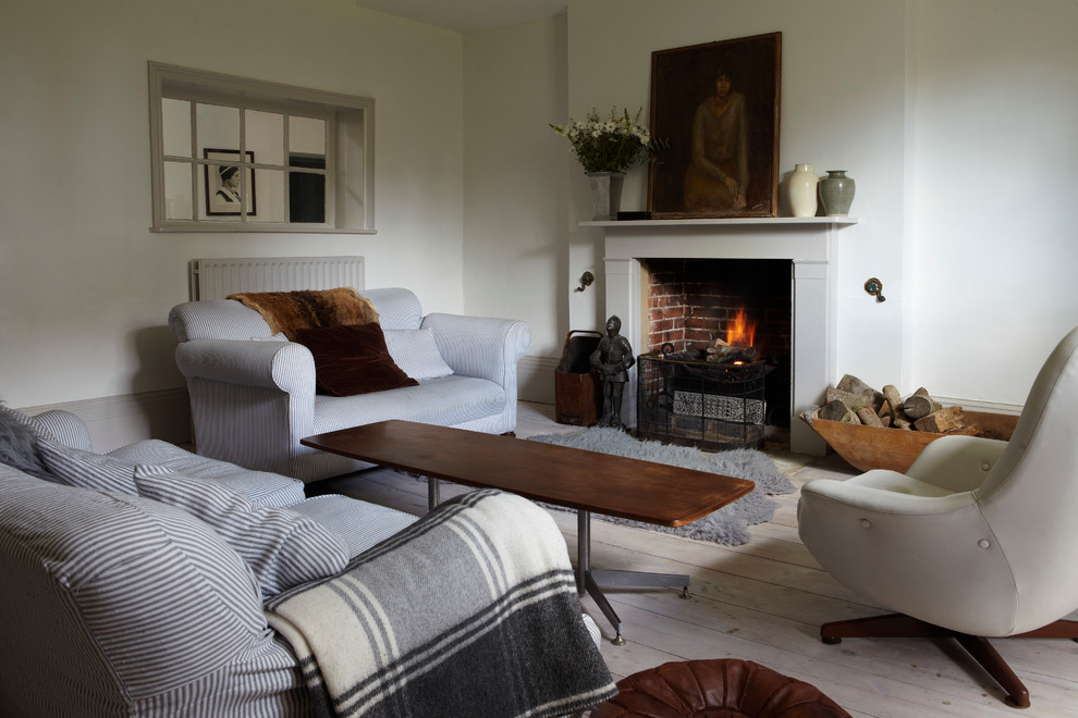 Mid-sized beach style enclosed living room in Dorset with white walls, painted wood floors, a standard fireplace and a wood fireplace surround.
