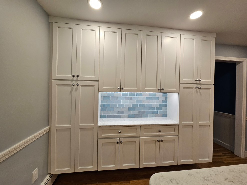 Bild på ett stort funkis vit vitt kök och matrum, med en undermonterad diskho, skåp i shakerstil, vita skåp, bänkskiva i kvarts, blått stänkskydd, stänkskydd i porslinskakel, rostfria vitvaror, mellanmörkt trägolv och en köksö