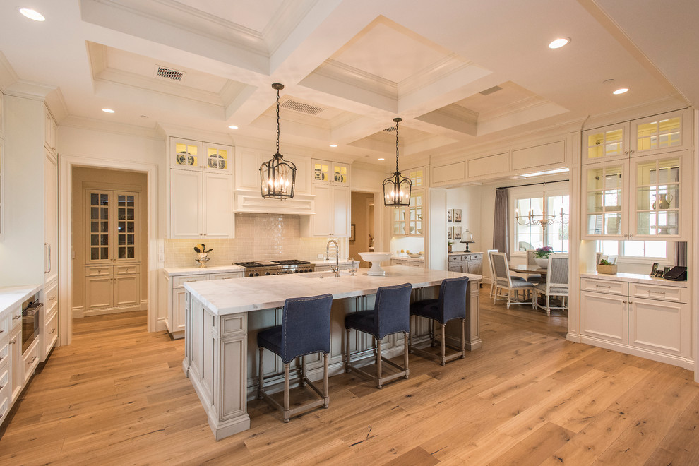 Inspiration for an expansive traditional u-shaped kitchen in Phoenix with recessed-panel cabinets, white cabinets, beige splashback, subway tile splashback, stainless steel appliances, medium hardwood floors and with island.