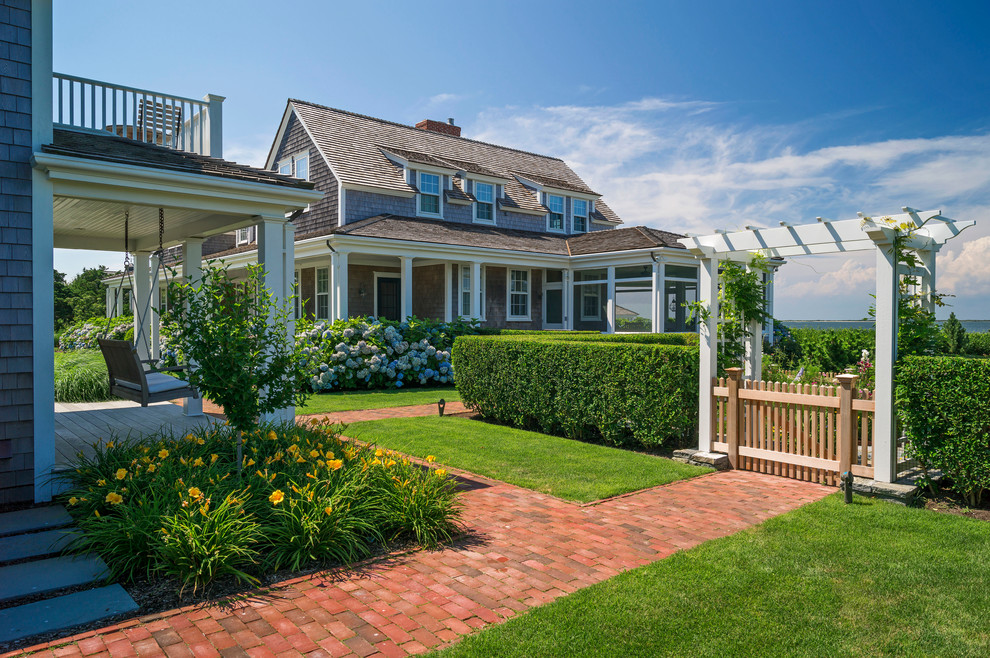 This is an example of an expansive beach style backyard full sun garden in Boston with brick pavers and a garden path.