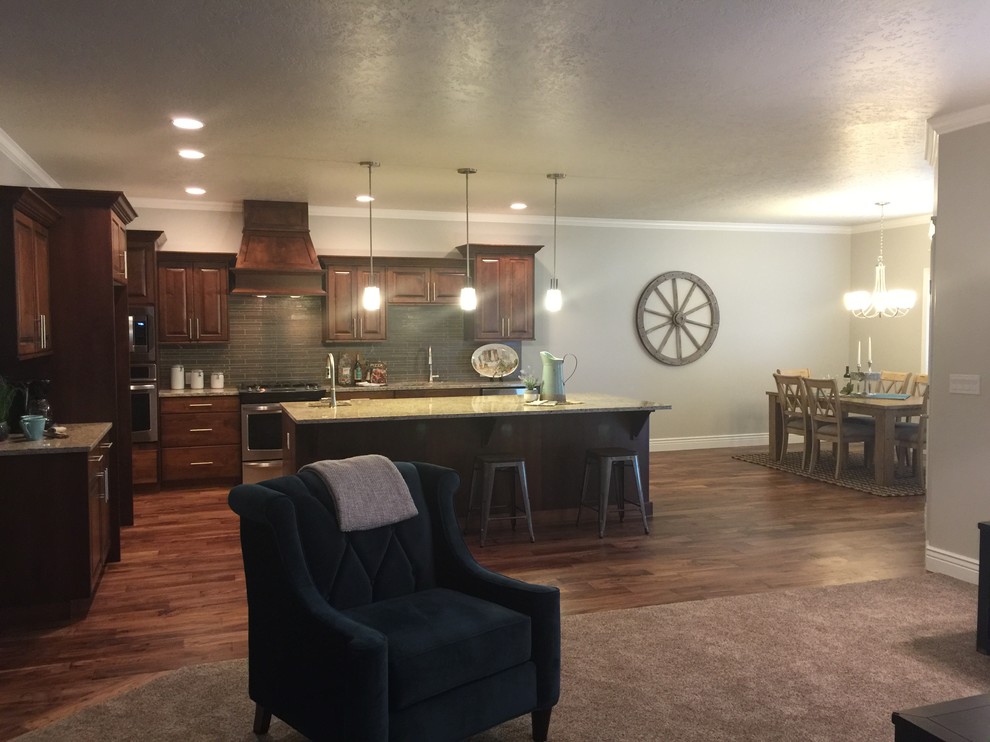 Inspiration for a mid-sized rustic l-shaped dark wood floor open concept kitchen remodel in Boise with an undermount sink, raised-panel cabinets, dark wood cabinets, granite countertops, gray backsplash, glass tile backsplash, stainless steel appliances and an island