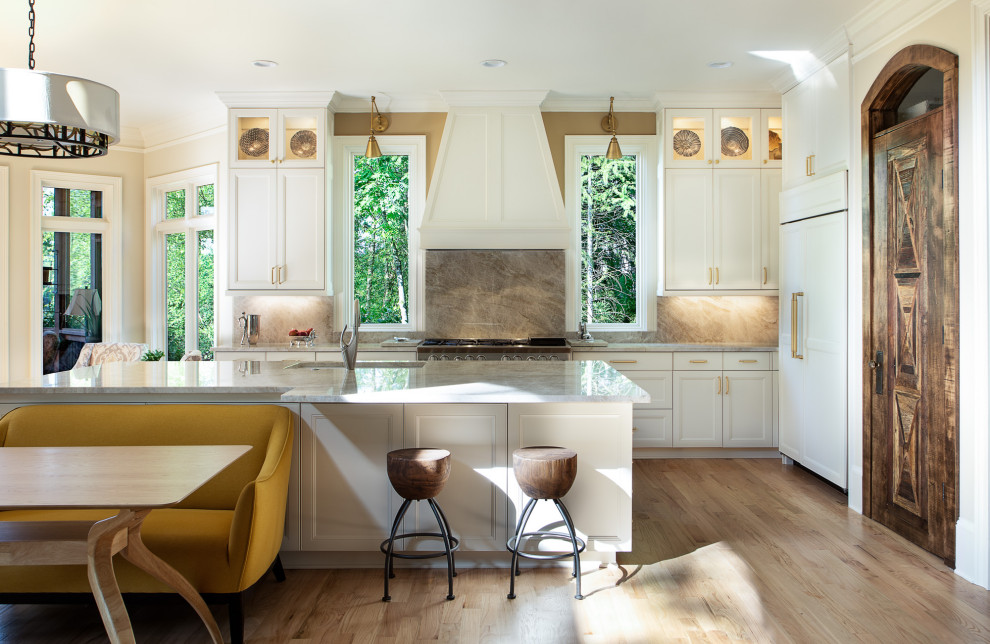 Country l-shaped eat-in kitchen in Atlanta with a single-bowl sink, shaker cabinets, white cabinets, grey splashback, stone slab splashback, panelled appliances, light hardwood floors, with island, beige floor and grey benchtop.