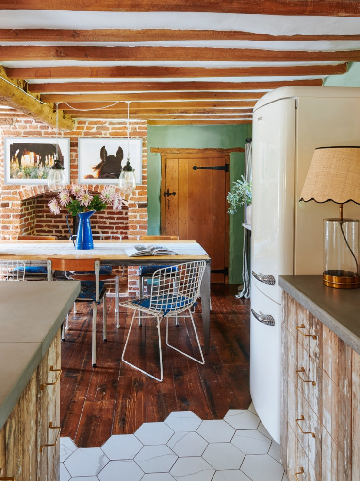 Пример оригинального дизайна: кухня среднего размера в стиле кантри с обеденным столом, с полувстраиваемой мойкой (с передним бортиком), плоскими фасадами, светлыми деревянными фасадами, столешницей из бетона, розовым фартуком, фартуком из керамической плитки, техникой под мебельный фасад, полом из керамогранита, островом, белым полом, серой столешницей и балками на потолке