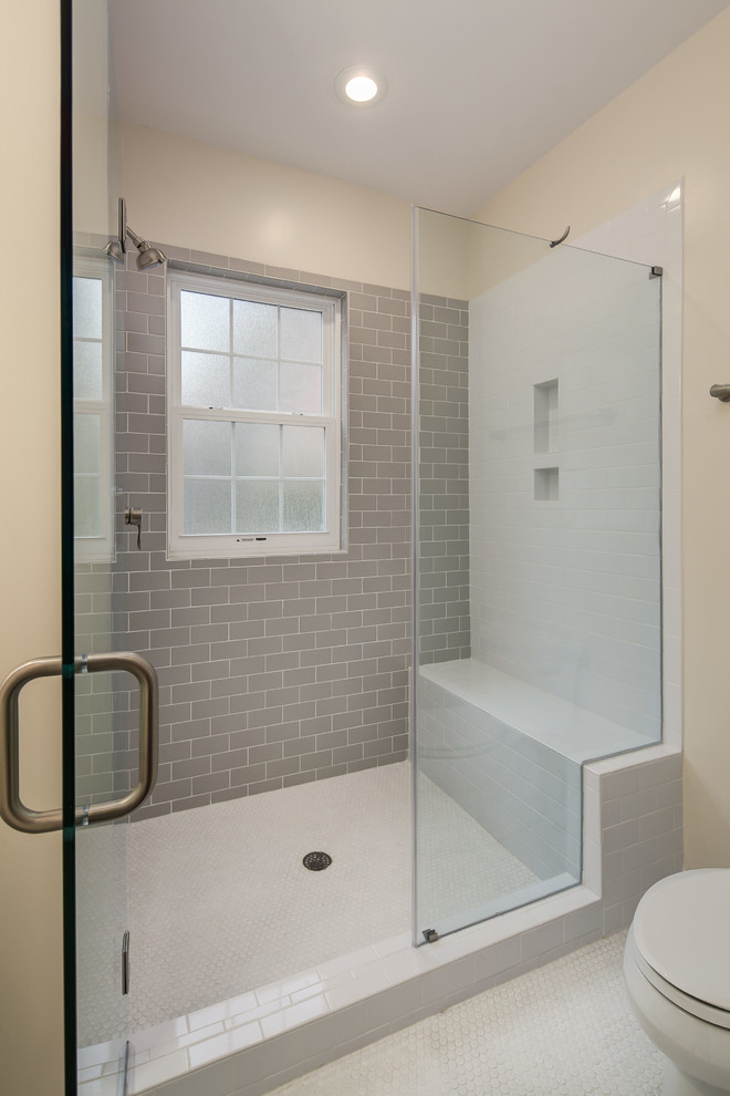 This is an example of a mid-sized transitional master bathroom in DC Metro with an alcove shower, a one-piece toilet, gray tile, subway tile, beige walls and linoleum floors.