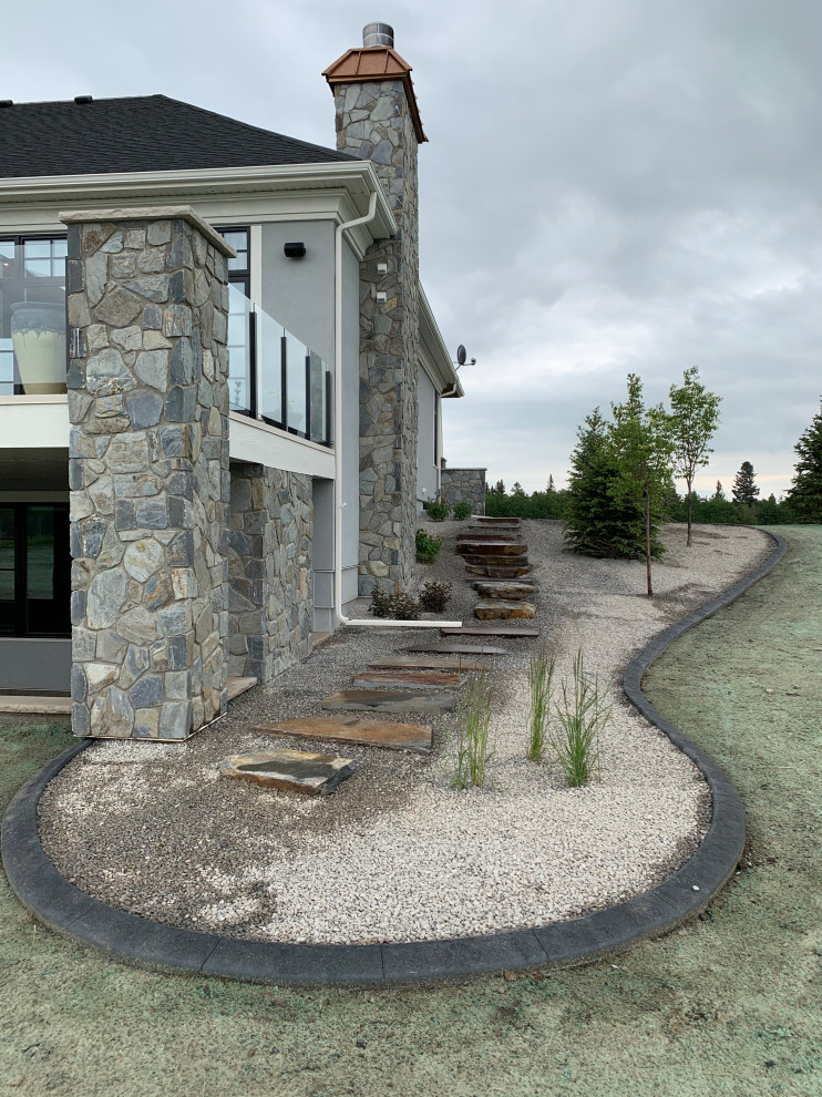 Expansive traditional sloped full sun xeriscape in Calgary with with lawn edging and natural stone pavers for fall.