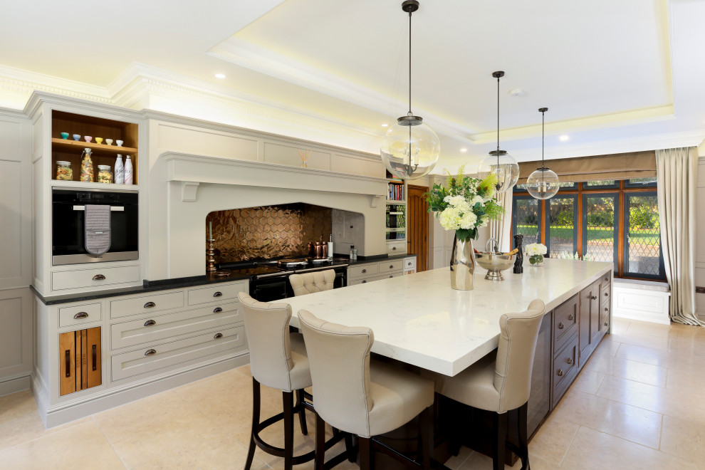 This is an example of a large traditional galley kitchen in Kent with recessed-panel cabinets, with island, white cabinets, metallic splashback, black appliances, beige floor and black benchtop.