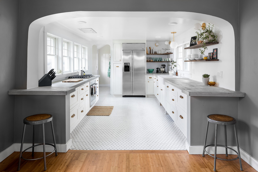 Inspiration for a mid-sized modern u-shaped kitchen in Atlanta with a farmhouse sink, recessed-panel cabinets, white cabinets, concrete benchtops, stainless steel appliances, ceramic floors, no island, white floor and grey benchtop.