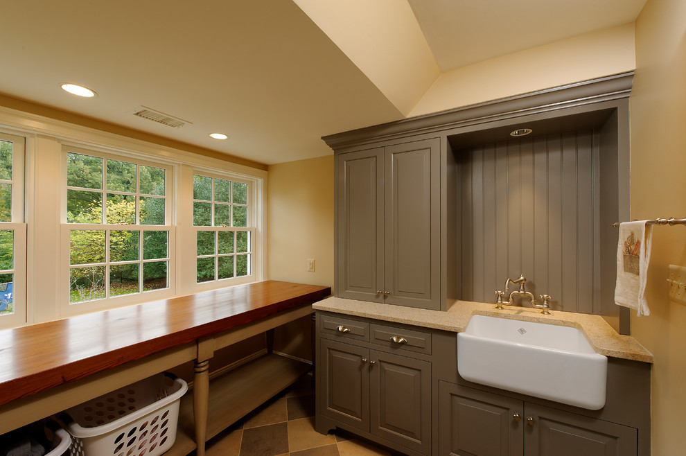 This is an example of a traditional laundry room in DC Metro with a farmhouse sink, wood benchtops, beige walls and beige benchtop.