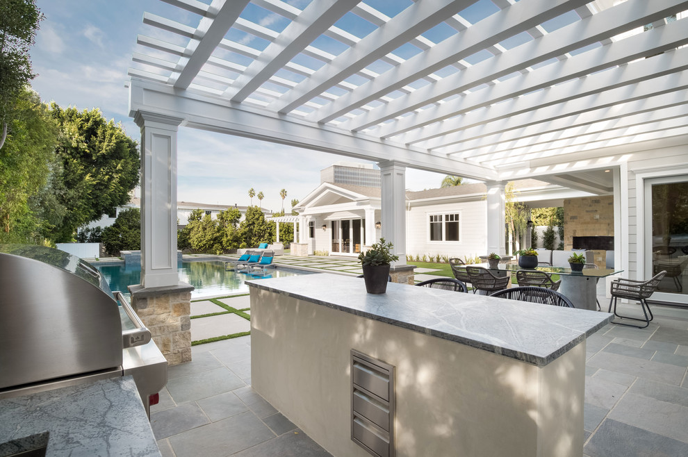 Large transitional backyard patio in Los Angeles with an outdoor kitchen, tile and a pergola.